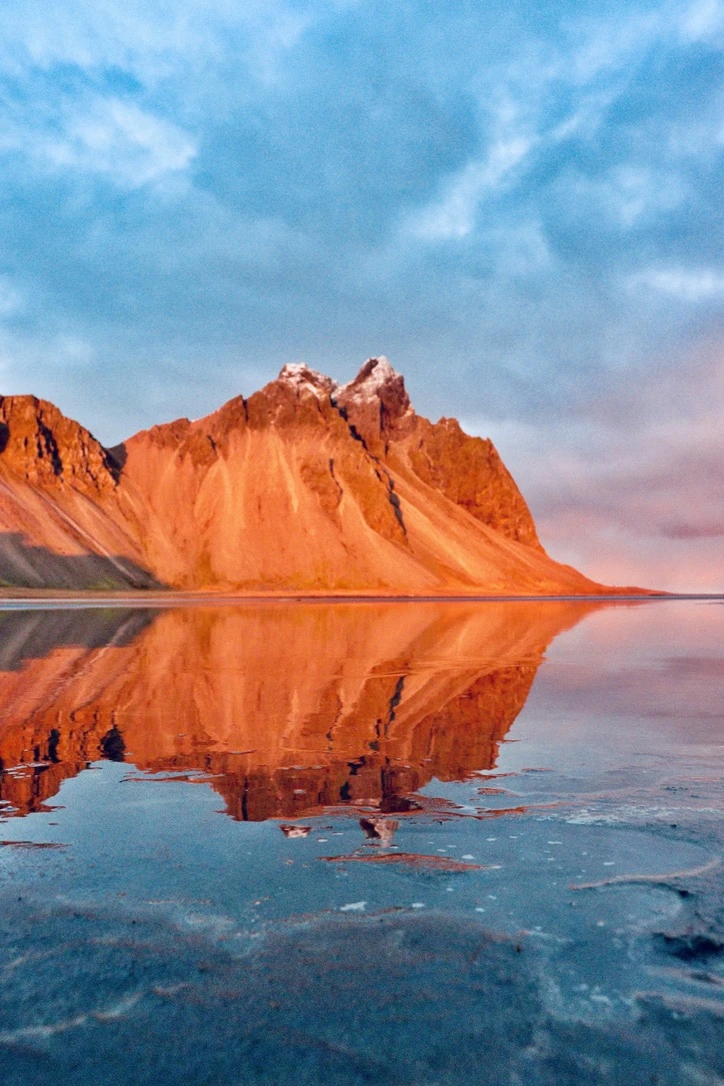 Orange mountain peaks reflected in still water