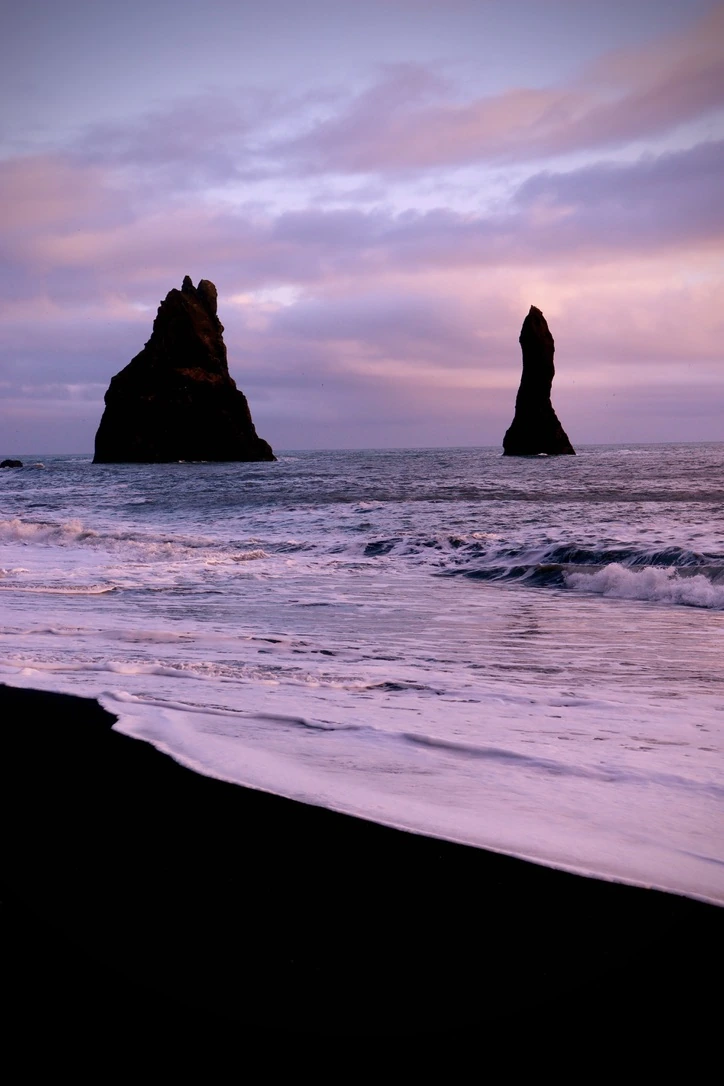 Sea stacks and breaking waves beneath a pink evening sky
